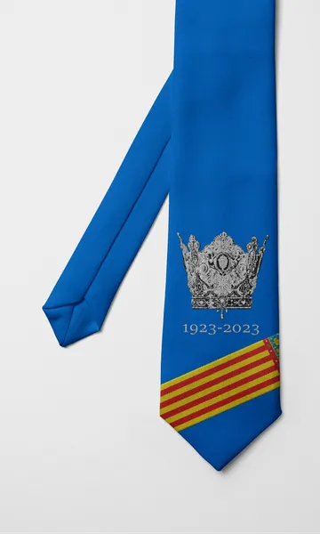 Corbata azul con una corona plateada, la inscripción 1923–2023 y franjas de la senyera en la punta