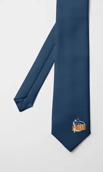 Corbata azul grisácea lisa con un emblema en la punta