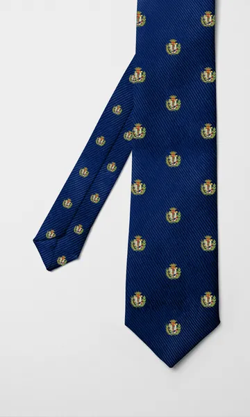 Corbata azul marino con el escudo colegial repetido en dorado