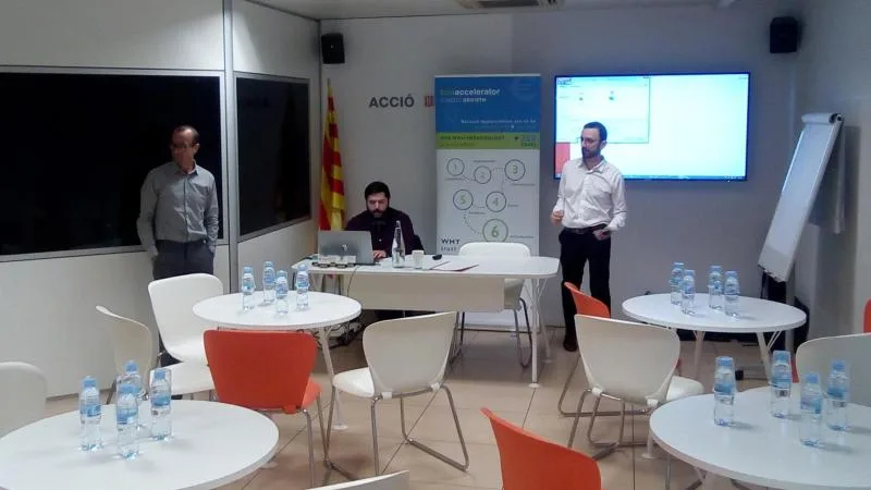 Sala de ACCIÓ preparada para el encuentro final, con el roll-up del programa y el equipo al fondo